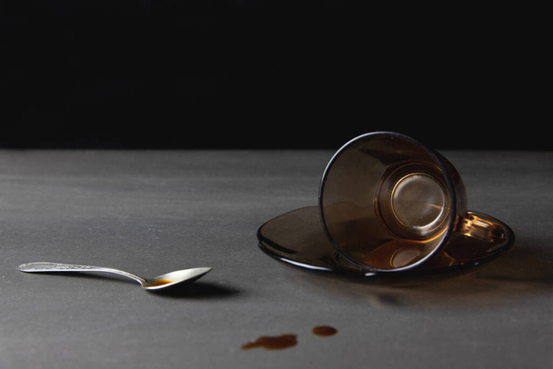 Spilled coffee, morning espresso, spilled brown glass of coffee, metal spoon, black background - Fotoğraf, Görsel