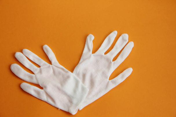 white protective gloves isolated on an orange background - Фото, изображение
