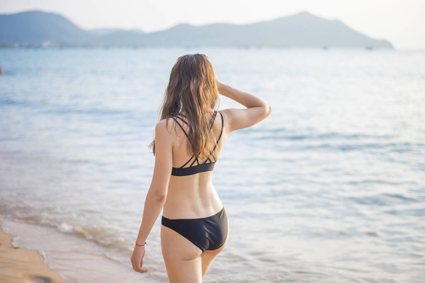 Beautiful woman in black bikini is relaxing on the beach, summer concept  - Photo, Image