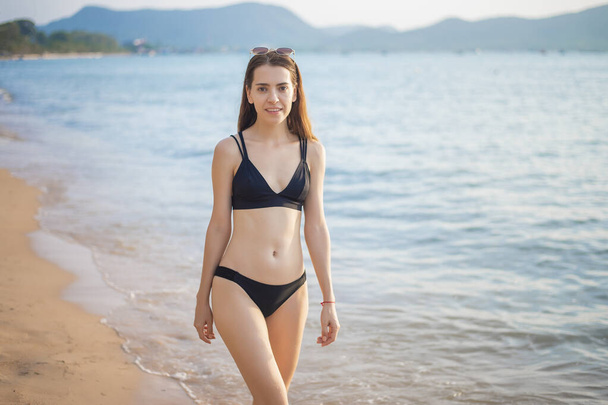Beautiful woman in black bikini is relaxing on the beach, summer concept  - Photo, image