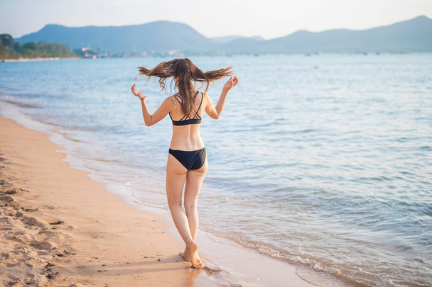Beautiful woman in black bikini is relaxing on the beach, summer concept  - Foto, Imagem