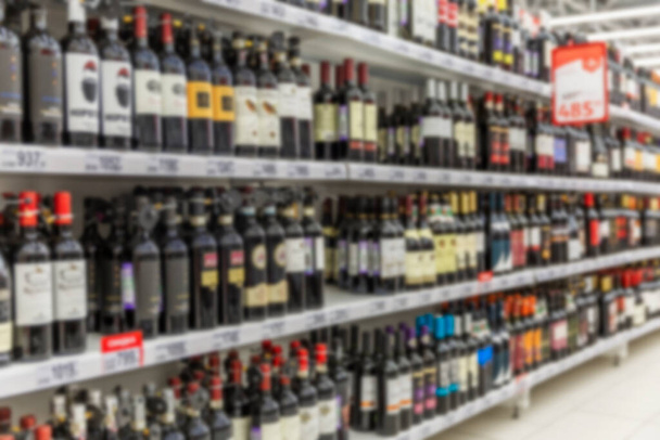 Rows of bottled alcohol of different kinds at a supermarket. Multiple colors, price tags. Blurred.  - Photo, image