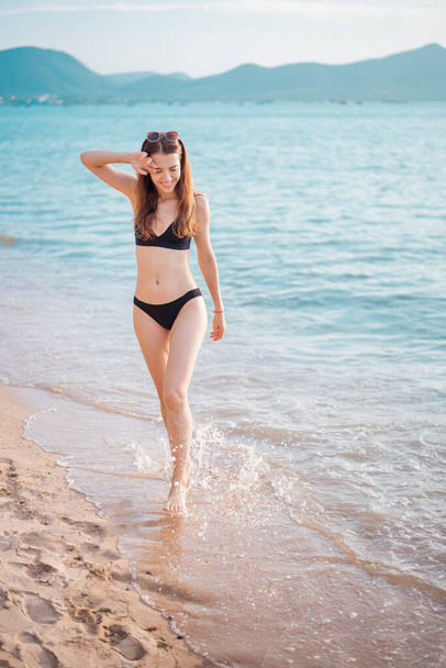 Beautiful woman in black bikini is walking from sea, summer concept  - Fotoğraf, Görsel