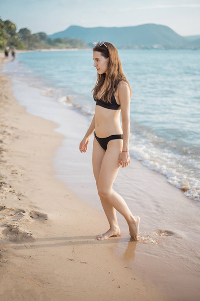 Beautiful woman in black bikini is walking from sea, summer concept  - Foto, Imagem