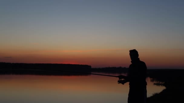Un hombre pescando - lanza la caña de pescar - silueta de puesta de sol
 - Imágenes, Vídeo