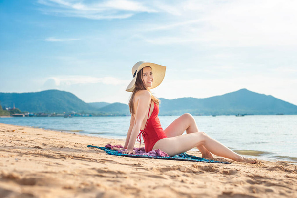 Beautiful woman in red swimsuit  is sitting on the beach  - Fotografie, Obrázek