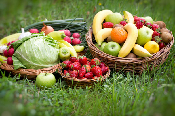 Fresh fruit and vegetable in basket on spring grass, healthy vegetarian food - Фото, изображение