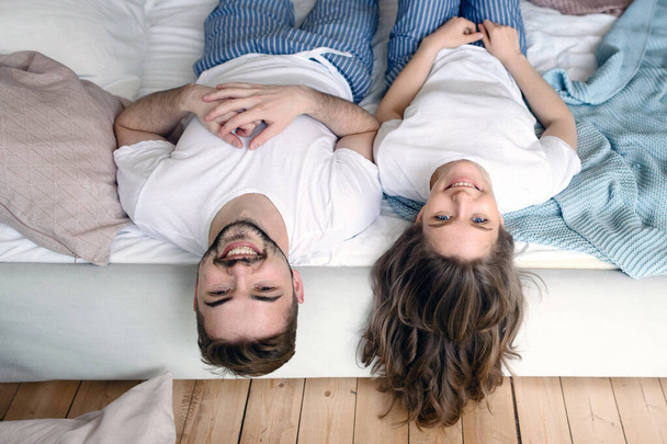 Jovem casal apaixonado está deitado na cama e rir
 - Foto, Imagem