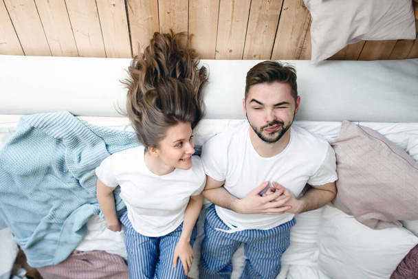Junges verliebtes Paar liegt auf dem Bett und lächelt - Foto, Bild