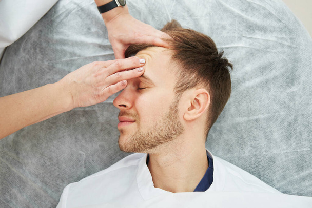 Handsome caucasian man has facial massage in cosmetologist's office close-up. Men's beauty procedures, beautician face skin care - Fotografie, Obrázek
