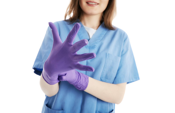 Optimistic medical staff putting on purple latex gloves for protection against viruses. Open hand. Isolated on white background. - Valokuva, kuva