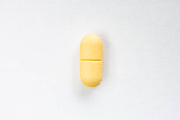 Yellow colored medicine pill capsule macro close up shot isolated on white surface 2020 - 写真・画像
