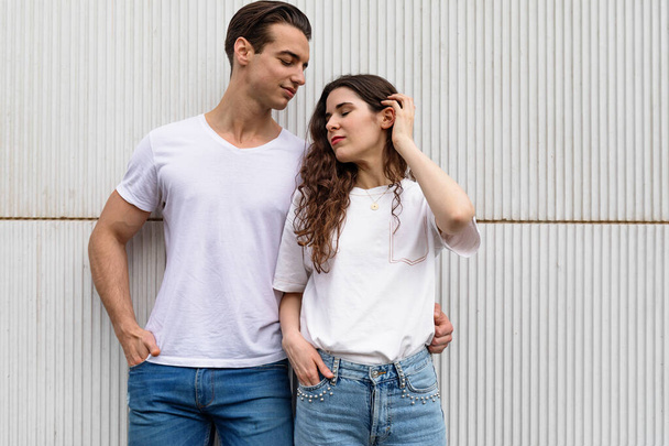Young couple standing together leaning on urban white wall - Foto, imagen