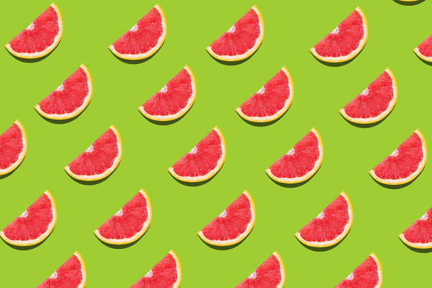 Flat lay fruit pattern of fresh grapefruit slices on green background. Minimal summer fruits pattern for blog or recipe book - Фото, зображення