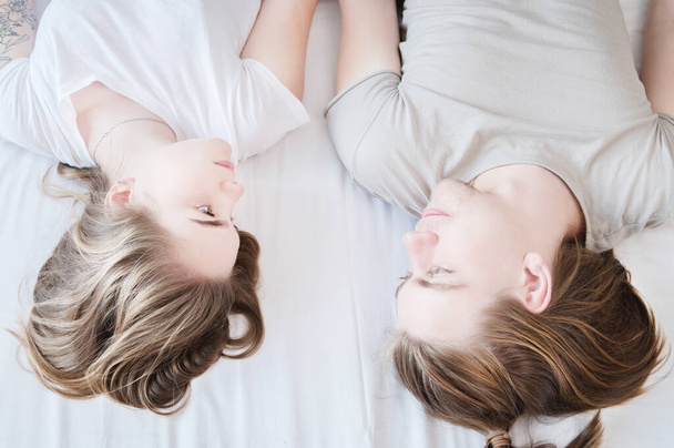 Top view portrait of a young couple with long hair lying on the bed and looking at each other. - Foto, Bild