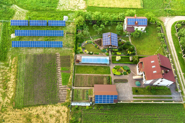 Vista aérea de una casa privada en verano con paneles solares fotovoltaicos azules en la azotea y en el patio
. - Foto, Imagen