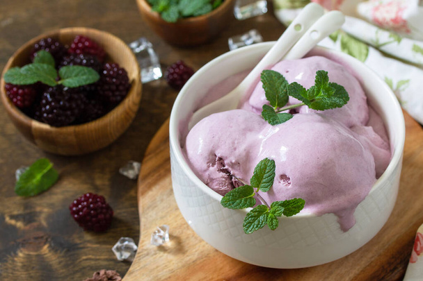 Домашнее органическое мороженое с мятой. Blackberry мороженое в белой миске на деревенском столе
. - Фото, изображение