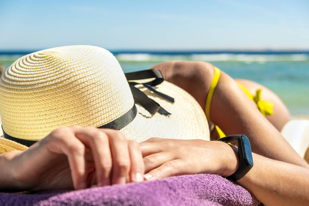 Primer plano de la mujer joven de cadera y hombro acostado en la silla de playa en la orilla del mar tomar el sol. - Foto, Imagen