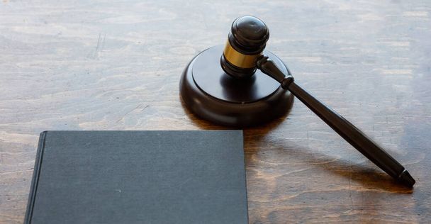 Téma práva. Soudce Gavel a černá prázdná právní kniha na pozadí dřevěného stolu, kopírovací prostor. Aukce, soudní stůl - Fotografie, Obrázek