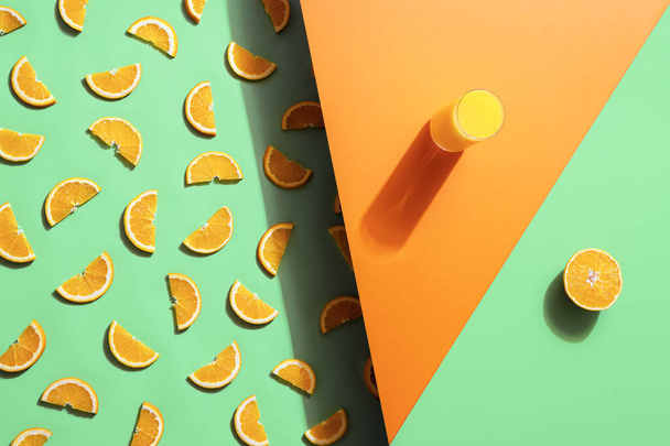 Sommergetränk, ein Glas Orangensaft und Fruchtscheiben auf nahtlosem grünen und orangefarbenen Hintergrund. Muster mit Orangenscheiben. Vitamin C-Drink. - Foto, Bild