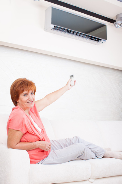 Woman holding a remote control air conditioner - Foto, Imagen