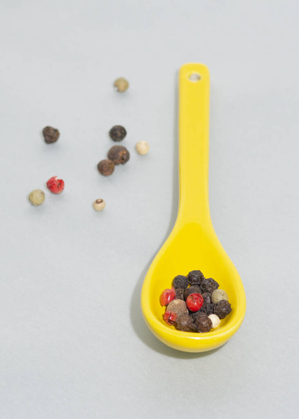 Close up of spoons of porcelain with mixture of peppercorn. Vertical view. Isolated object. - Photo, Image