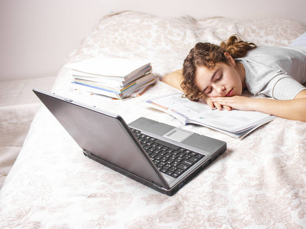 Дівчина-підліток на карантині вивчає онлайн на своєму ліжку. Домашнє навчання
 - Фото, зображення