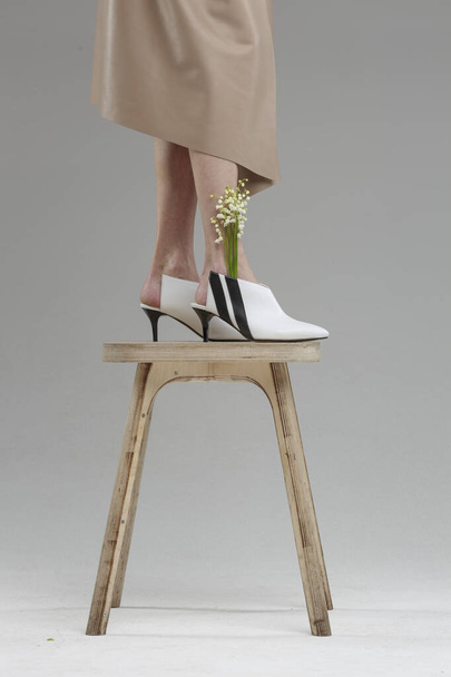 Ноги в обуви красивой молодой женщины, стоящей на стуле у стены, без бренда, копировальное место
 - Фото, изображение