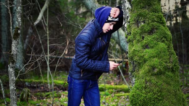 smutně chlapec s mobil se opíral o strom - Záběry, video