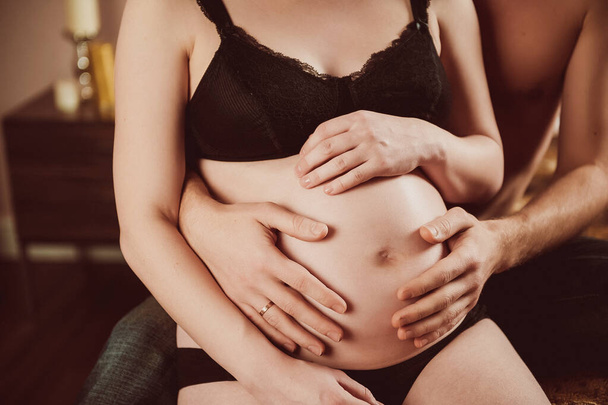 a pregnant woman holds her stomach with her husband - Fotoğraf, Görsel