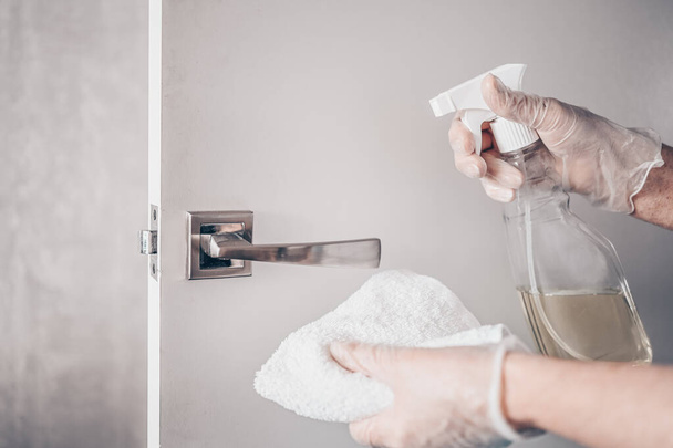 Coronavirus COVID-19 Prevention cleaning woman wiping doorknob with antibacterial disinfecting spray for killing corona virus on touching surfaces or touching public bathroom handle with tissue. - 写真・画像