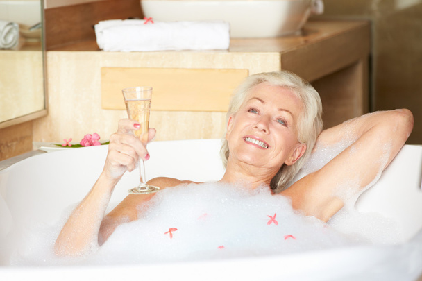 Senior Woman Relaxing In Bath Drinking Champagne - Фото, изображение