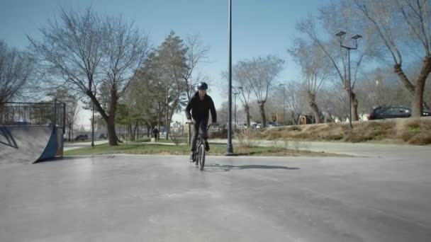 Een jonge bmx rijder doet trucs op pijp in skate park. - Video
