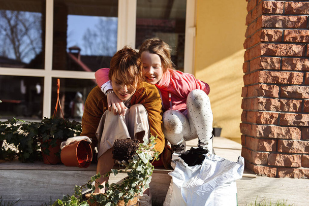 Mom with daughter planting flowers on the terrace of the house - 写真・画像