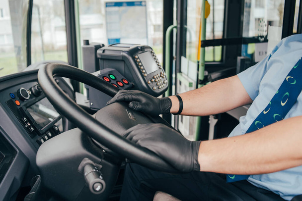 jonge Spaanse buschauffeur met blauw medisch masker draagt zwart beschermende handschoenen op zijn hand in de bus om zichzelf te beschermen tegen de coronavirus epidemie. Covid 19, beschermen tegen het corona virus. quarantaine 2020. thuisblijven - Foto, afbeelding