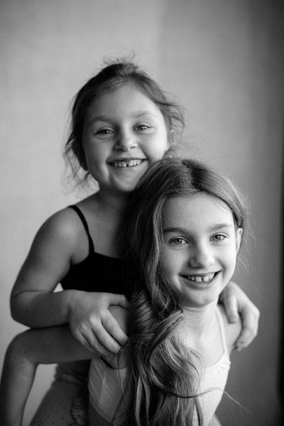 Black and white portrait of two little systerichka girls hugging each other and laughing joyfully. Family values. Friendship. Joy - Fotoğraf, Görsel