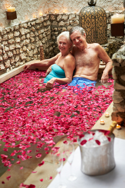 Casal sênior relaxante na piscina coberta de pétalas de flor no spa
 - Foto, Imagem