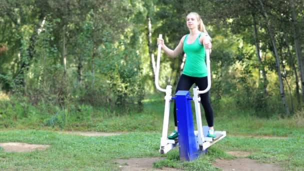 zdrowy sprawny młoda kobieta ćwiczenia na trenera w ogrodzie - Materiał filmowy, wideo