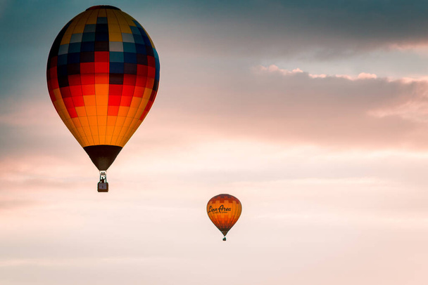 Flying hot air balloons through the sky during sunset at an airshow in Battle Creek Michigan - Photo, Image
