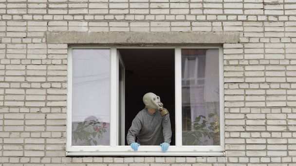 A gázálarcos öregember otthon marad az ablakban elszigetelve a karanténban. Koronavírus - Fotó, kép