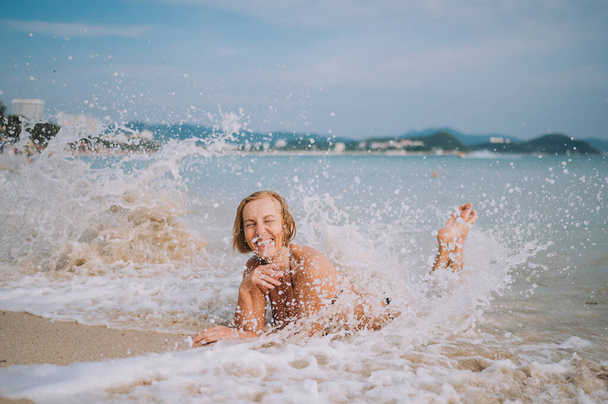 Šťastný úsměv vzrušený starší žena turista hrát ve vodě a koupání ve velkých vlnách na mořské pláži oceánu. Cestování po Asii, aktivní životní styl koncept. - Fotografie, Obrázek