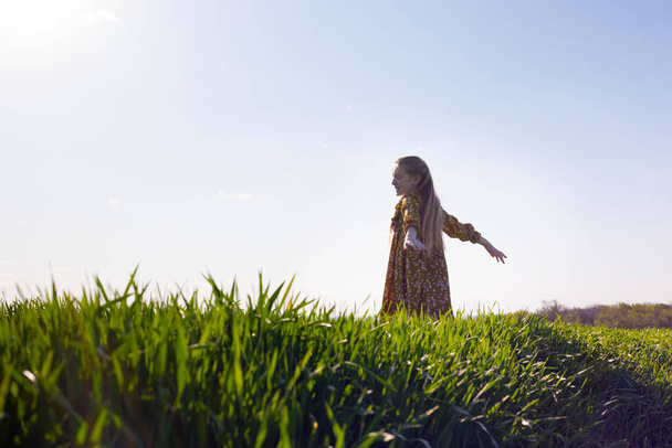 happy girl is joyful spinning in the green field. summer and freedo - Foto, afbeelding