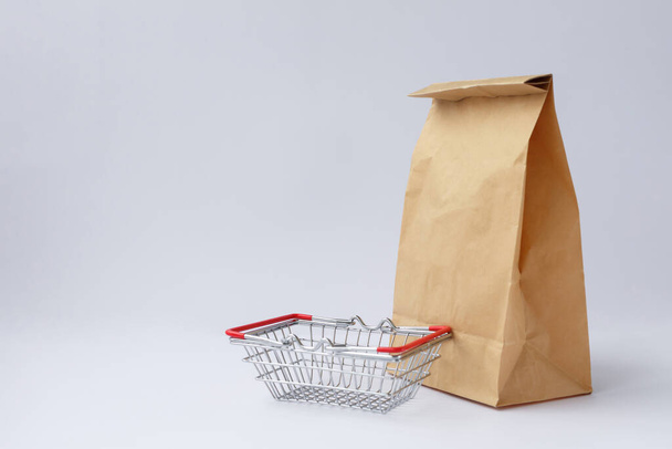 brown craft paper bag for shopping on a white background and a small grocery basket - Photo, Image