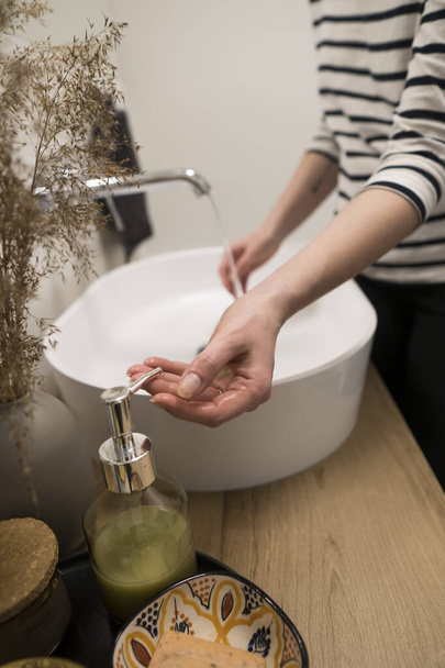 COVID-19 Coronavirus. Woman washing hands with foam soap and hot water at bathroom. Hygiene, preventing coronavirus. Corona Virus pandemic protection by cleaning hands frequently. - 写真・画像