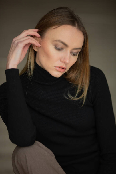 close up portrait of stylish looking girl in black turtleneck with blue eyes, model posing in interior, studio background  - Photo, image
