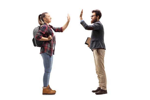 Full length profile shot of a female student gesturing high-five with a male teacher isolated on white background - Foto, immagini