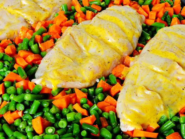Στήθη κοτόπουλου σε σάλτσα μουστάρδας με λαχανικά πριν το ψήσιμο. Πράσινα μπιζέλια, καρότα, πράσινα φασόλια. Η έννοια της υγιεινής διατροφής και της απώλειας βάρους. - Φωτογραφία, εικόνα