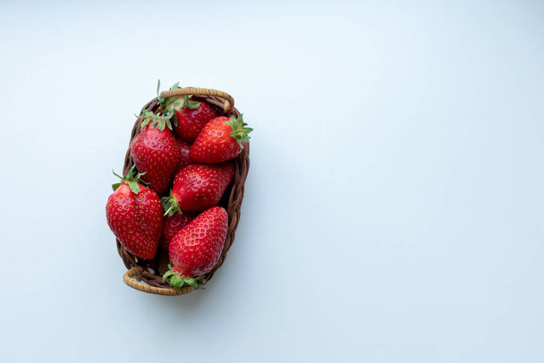 Erdbeeren in einem geflochtenen Korb auf weißem Hintergrund - Foto, Bild