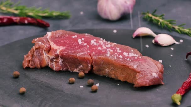 Widok obrotowy soczystego surowego mięsa stekowego solonego i przyprawionego. - Materiał filmowy, wideo