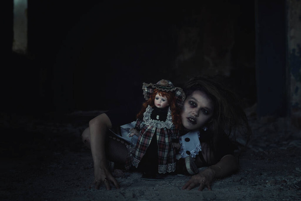 eng meisje met een pop in een verlaten huis - Foto, afbeelding